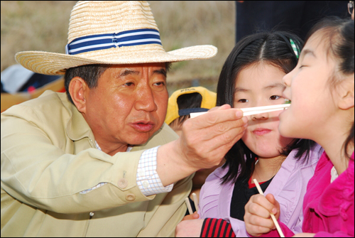 2008년 서거 전 김해 봉하마을을 찾는 초등학생에게 먹을 것을 입에 넣어주는 노무현 전 대통령의 모습. 노 전 대통령의 특유의 소탈한 모습으로 퇴임 후 큰 사랑을 받았다. 