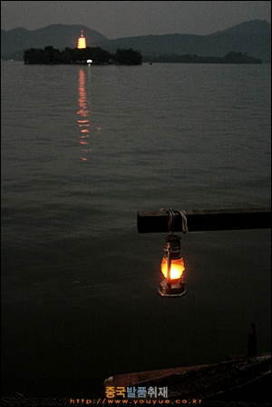 항저우 레이펑탑이 조명이 빛나고 있고 밤배놀이를 하는 배 호롱불과 나란하다