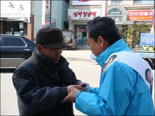 태백 거리에서 유권자의 손을 잡은 최 후보. "힘드시죠? 경제 반드시 살려내겠습니다."