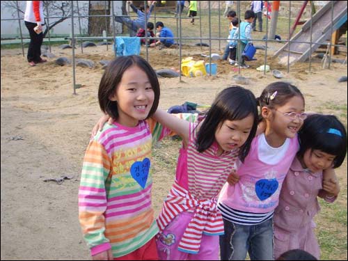 어린이집 터전 마당에서 동무들과 어깨동무 하고 놀고 있는 아이들