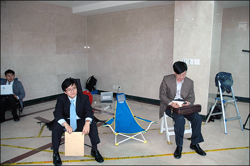 조준웅 특검팀의 거부로 특검기자실에서 쫓겨난 박원석 참여연대 협동처장(좌측)과 김상조 한성대 교수(우측)가 특검 사무실 2층 로비에 놓인 촬영기자들의 의자에 앉아 기다리고 있다.