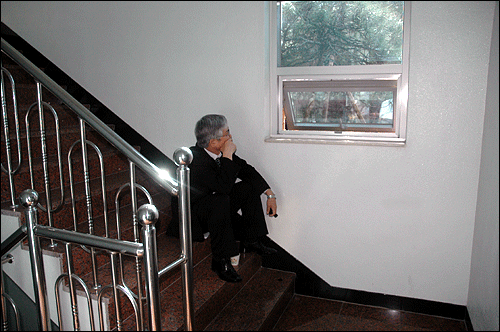 삼성특검의 거부로 특검 기자실에서 쫓겨난 이덕우 변호사가 계단에 쭈그리고 앉아 창밖을 응시하고 있다.