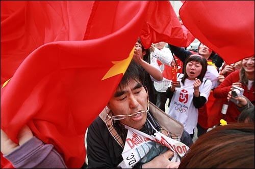 27일 오후 서울 올림픽공원에서 북경올림픽 성화봉송행사가 열리는 가운데 평화의문 부근에서 탈북자 문제 등 중국인권상황을 규탄하는 시위를 벌이던 시민단체 회원에게 중국 유학생들이 깃발을 휘두르며 옷을 잡아 당기고 있다.