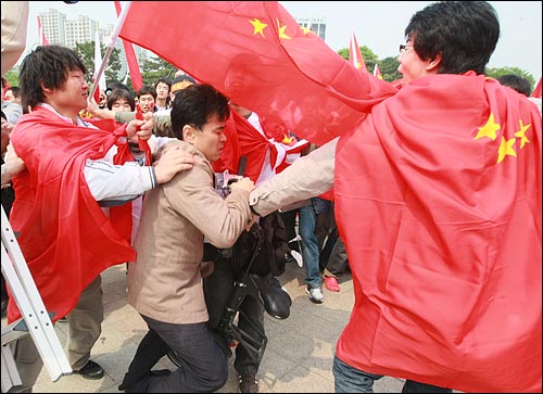 4월 27일 오후 서울 송파구 올림픽공원 평화의 문 광장앞에서 성화가 출발한 뒤 중국 유학생들과 중국의 인권 탄압에 반대하는 시민단체 회원들이 충돌한 가운데 한 시민이 중국 유학생들의 폭행을 피해 빠져나오고 있다.