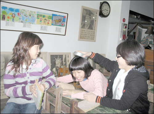 송학민속체험박물관은 '체험천국'이다. 같은 학교 친구인 슬비와 산하가 1970년대 학교교실에 앉아 장난을 하고 있다.