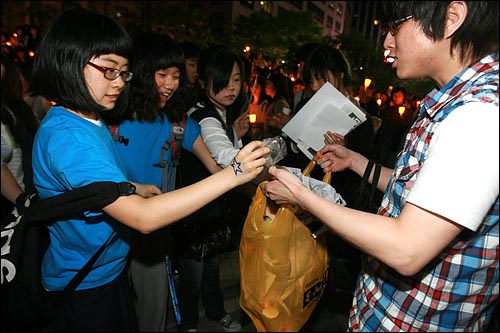미국산 쇠고기 수입 전면 개방을 반대하는 학생과 시민들이 3일 저녁 서울 청계광장에서 촛불문화제를 열었다. 집회가 마친 뒤 참가자들이 쓰레기를 봉투에 모으고 있다.