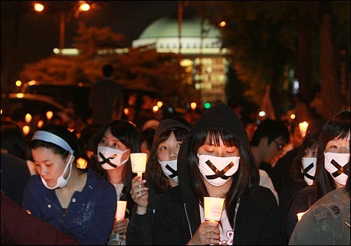 미국산 쇠고기 수입 전면 개방을 반대하는 학생과 시민들이 6일 저녁 서울 여의도 공원 앞에서 열린 촛불문화제에서 정부의 미국산 쇠고기 수입 정책 철회를 촉구하며 촛불을 들고 침묵시위를 하고 있다. 참가자 등뒤로 국회의사당이 보이고 있다.
