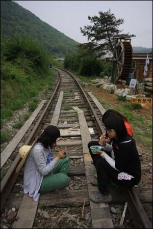 문경 진남역은 사용하지 않는 철로를 자전거 철도로 이용하고 있다. 강강수월래단 단원들이 철로에 앉아 아침 식사를 하고 있다. 