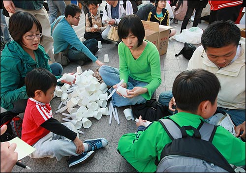 미국산 쇠고기 수입 전면 개방을 반대하는 학생과 시민들이 14일 저녁 서울 시청앞 잔디광장에서 열린 촛불문화제 시작전 종이컵에 양초를 끼우며 준비를 하고 있다.