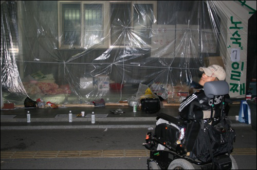 청주시청 본관 옆 간이 천막 앞에서 한 장애인이 휠체어를 타고 주변을 돌고 있다