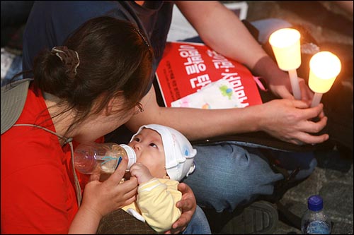  17일 저녁 서울 청계광장에서 열린 광우병위험미국산쇠고기 수입반대 촛불문화제에 한 부부가 갓난아기를 데리고 참석하고 있다.