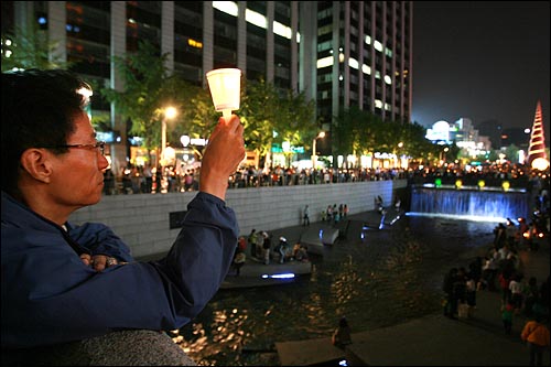 한 시민이 모전교 위에서 촛불을 높이 들고 있다.