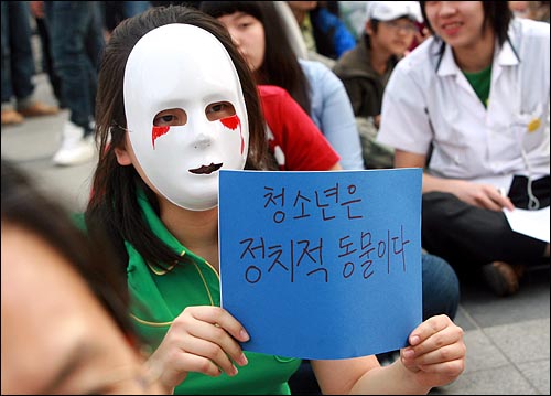 17일 오후 서울 덕수궁앞에서 열린 '미친소, 미친교육, 청소년이 바꾼다! 5.17 청소년 행동의날' 행사에서 가면을 쓴 한 학생이 '청소년은 정치적 동물이다'는 글이 적힌 종이를 들고 있다.