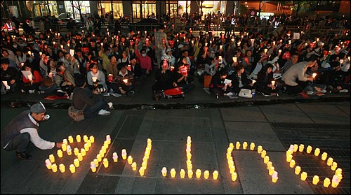미국산 쇠고기 수입 전면 개방을 반대하는 시민이 21일 저녁 서울 청계광장에서 열린 촛불문화제에서 정부의 미국산 쇠고기 수입 정책 철회를 촉구하며 촛불로 "OUT MB"라고 글자를 만들고 있다.