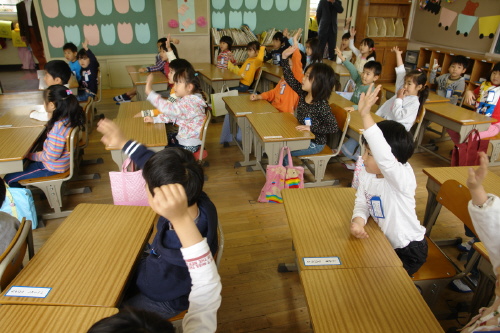 일본 도쿄 가미히라이 초등학교 학생들이 아침독서를 한 뒤에 교사의 질문에 답하기 위해 서로 손을 들고 있다.