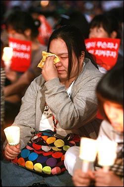 25일 저녁 서울 청계광장에서 열린 광우병위험 미국산쇠고기 수입반대 촛불문화제에서 분신자살 시도 소식이 알려진 가운데 한 참석자가 눈물을 닦고 있다.