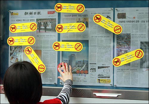 규탄기자회견을 연 뒤, 조선일보 게시판에 항의 스티커를 붙이고 있다.