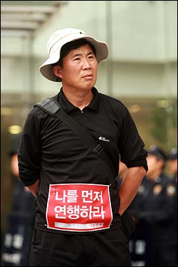  광우병위험 미국산쇠고기 수입반대 21차 촛불문화제가 열리는 28일 저녁 서울 청계광장에서 한 시민이 '나를 먼저 연행하라'는 글이 적힌 천에 자신의 이름을 적어서 옷에 붙이고 있다.