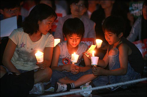 28일 저녁 서울 청계광장에서 열리는 광우병위험 미국산쇠고기 수입반대 21차 촛불문화제에서 가족들이 촛불을 들고 있다.
