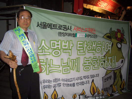 30일 저녁 시청광장에서 김선구 전 서울지하철노조위원장이 '소명박 탄핵하여 하느님께 봉헌하자'가 적힌 현수막을 펼쳐보이고 있다.