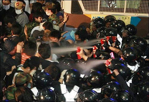 지난 1일 밤 서울 세종로 사거리에서 미국산 쇠고기 수입반대를 요구하며 시위를 벌이던 학생, 시민들에게 경찰들이 근접분사기를 분사하고 있다.