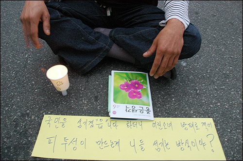 1일 광주 금남로에서 열린 촛불집회에 한 시민이 자신이 만든 종이선전물을 아스팔트에 펼쳐놓고 있다.
