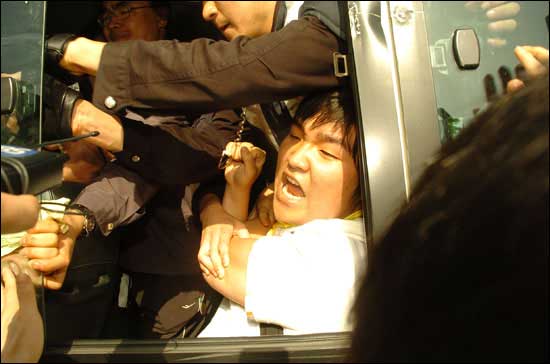 강제 연행된 시위 참가자가 호송차 밖으로 연행의 불법성을 성토하고 있다.