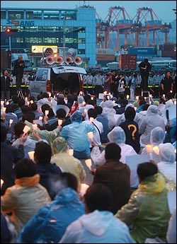 농림수산식품부가 미국산 쇠고기 수입위생조건 관보 게재를 유보한 가운데 민주노총 부산본부와 시민단체회원들이 2일 오후 부산 감만부두 앞에서 광우병 미국산 쇠고기 운송저지투쟁 촛불문화제를 열고 고시 철회와 재협상을 요구하며 구호를 외치고 있다.