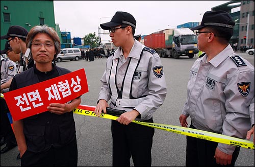 농림수산식품부가 미국산 쇠고기 수입위생조건 관보 게재를 유보한 가운데 한 시민이 2일 오후 부산 감만부두 앞에서 광우병 미국산 쇠고기 운송저지투쟁 촛불문화제에 참석하여 고시 철회와 재협상을 요구하며 손피켓을 들어보이고 있다.