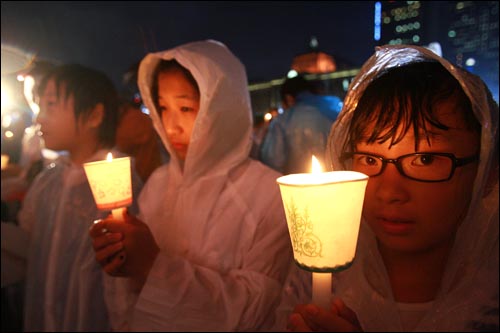 2일 저녁 서울시청 앞 광장에서 폭우가 쏟아지는 가운데 열린 광우병 위험 미국산 쇠고기 수입 반대 및 재협상을 촉구하는 26차 촛불 문화제에서 학생들이 촛불을 들고 있다.