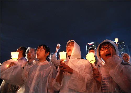 2일 저녁 서울시청앞 광장에서 폭우가 쏟아지는 가운데 열린 광우병위험 미국산 쇠고기 수입반대 및 재협상을 촉구하는 26차 촛불문화제에서 학생들이 촛불을 들고 함성을 외치고 있다.