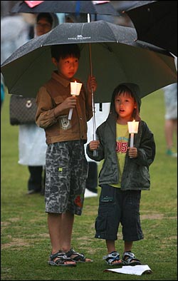 이명박 대통령 취임 100일을 맞이한 3일 저녁 폭우가 쏟아지는 가운데 서울시청앞 광장에서 열린 광우병위험 미국산쇠고기 수입반대 및 재협상을 촉구하는 27차 촛불문화제에서 우산을 든 학생들이 참석하고 있다.