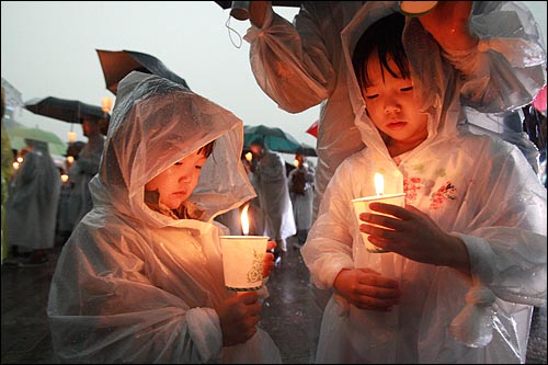 2일 저녁 서울시청앞 광장에서 폭우가 쏟아지는 가운데 열린 광우병위험 미국산 쇠고기 수입반대 및 재협상을 촉구하는 26차 촛불문화제에서 어린이들이 촛불을 지켜보고 있다.