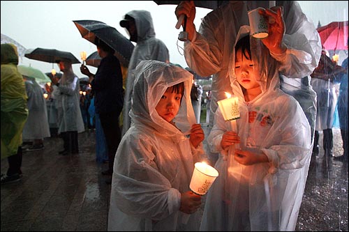 2일 저녁 서울시청앞 광장에서 폭우가 쏟아지는 가운데 열린 광우병위험 미국산 쇠고기 수입반대 및 재협상을 촉구하는 26차 촛불문화제에서 어린이들이 촛불을 들고 있다.