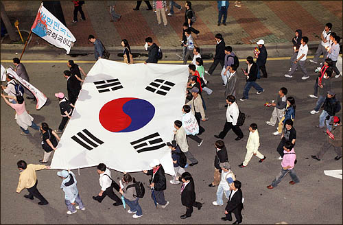 5일 밤 서울 세종로 사거리에서 미국산 쇠고기 수입에 반대하며 밤샘 농성을 벌이던 일부 시민들이 서대문 경찰청으로 이동, 폭력진압에 항의한 뒤 태극기를 앞세워 거리행진을 하고 있다. 