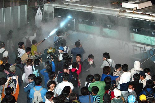 미국산 쇠고기 수입 전면 개방 반대 72시간 릴레이 농성 세 번째날인 7일 새벽 서울 신문로 한글회관 앞에서 경찰 버스를 끌어내려는 시민, 학생들에게 경찰이 소화기를 뿌리고 있다.