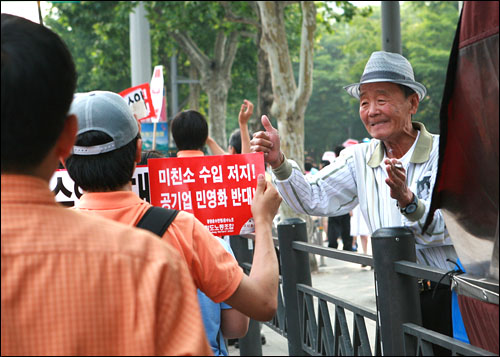 7일 오후 서울 대학로 마로니에 공원에서 출발한 미국 쇠고기 수입반대 및 재협상 요구 시위대가 서울 시청 앞 광장을 향해 행진하고 있는 가운데 종묘 앞에서 한 노인이 시위대에게 환호를 보내고 있다.