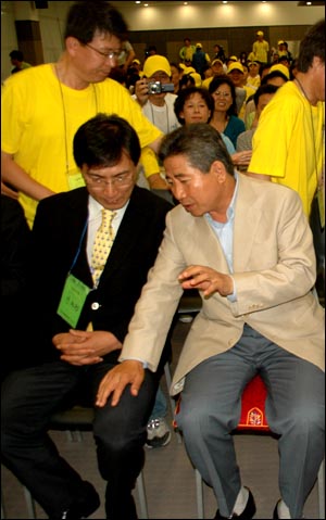 노무현 전 대통령이 안희정씨의 허벅지에 손을 짚고 이야기를 나누고 있다.
