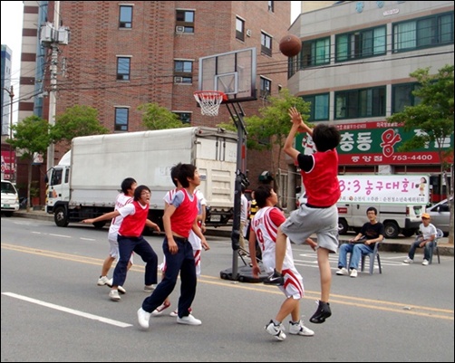 차가 없는 거리에서 길거리 농구를 하고 있는 아이들