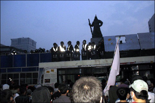 6월 8일 새벽, 광화문 이순신 동상 앞에서 경찰과 대치중인 시민들. 이순신 장군이 수난을 당하고 있다. 한 시민은  너무 안스럽다며, 이순신 장군 동상을 돌려 세우자는 제안을 했다.