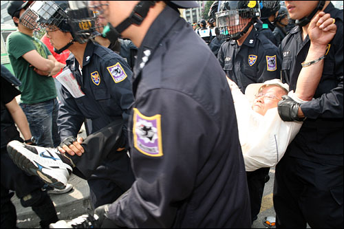 11일 오전 세종로 사거리 차도에서 연좌농성을 하고 잇던 시위대를 경찰이 강제연행하기 시작, 한 노인이 사지를 붙들린채 연행되고 있다.