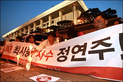 13일 저녁 여의도 KBS앞에서 이명박 정권 공영방송 장악음모 저지를 위한 촛불집회를 열고 있는 시민들이 '퇴진 최시중, 사수 정연주'가 적힌 현수막을 들고 있다.