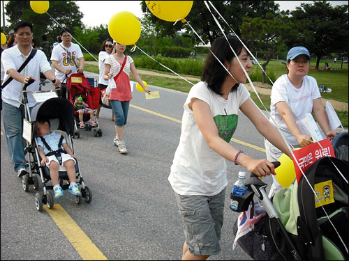유모차를 이끌고 나온 주부들이 한강시민공원에 모여 국회의사당을 향해 행진하고 있다.
