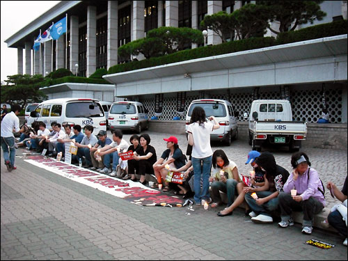 14일 오후 KBS 앞에서 '공영방송 지키기' 촛불집회 시작에 앞서 일부 시민들이 앉아있다.