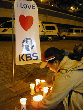 한 시민이 'I love KBS'라는 펼침막 앞에서 촛불을 들고 있다.