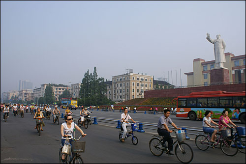 지난 10일 원촨 대지진 발생 한 달을 앞두고 청두 중심가 텐푸(天府)광장 마오쩌둥(毛澤東) 동상 앞을 자전거로 힘차게 달리는 청두 시민들.
