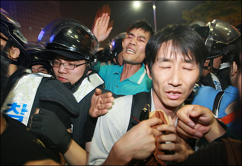 미국산 쇠고기 수입 정책 철회와 전면 재협상을 요구하며 시위를 벌이던 시민들이 20일 밤 서울 세종로 네거리에서 경찰들에게 강제로 인도로 밀어 올려지며 강제 해산되고 있다.