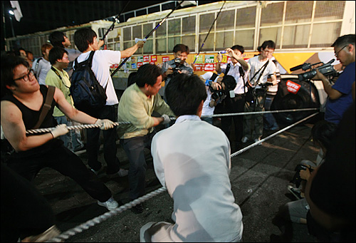 미국산 쇠고기 수입 정책 철회와 전면 재협상을 요구하며 시위를 벌이던 시민들이 21일 새벽 서울 세종로 네거리에서 전경버스를 밧줄로 묶어 끌어내려고 시도하고 있다.