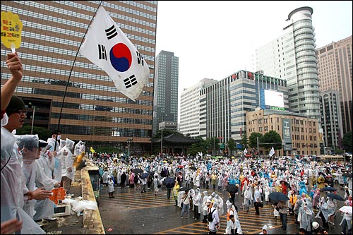 한미 쇠고기 재협상을 촉구하는 48시간 릴레이 농성이 벌어지는 가운데 22일 새벽 서울 세종로네거리에서 밤새 경찰과 격렬하게 대치했던 시민, 학생들이 태극기를 들고 경찰버스 위에 올라가서 노래를 부르고 있다.