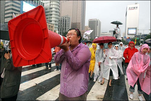 한미 쇠고기 재협상을 촉구하는 48시간 릴레이 농성이 벌어지는 가운데 22일 새벽 서울 세종로네거리에서 밤새워 시위를 벌였던 한 시민이  교통안전시설물을 확성기로 사용해서 노래를 부르고 있다.